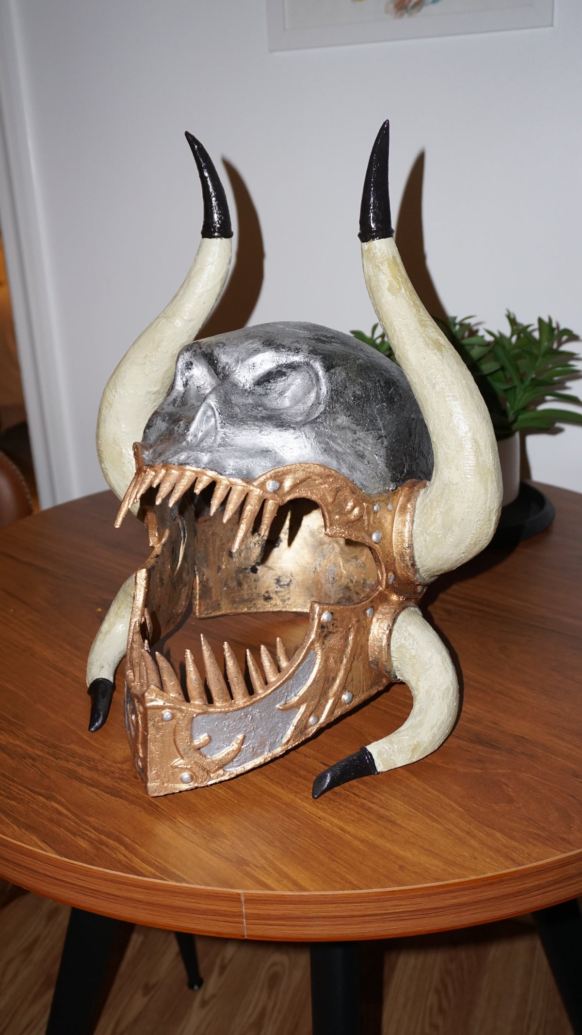 a unique and intricate sculpture of a skull with horns, displayed on a wooden table.