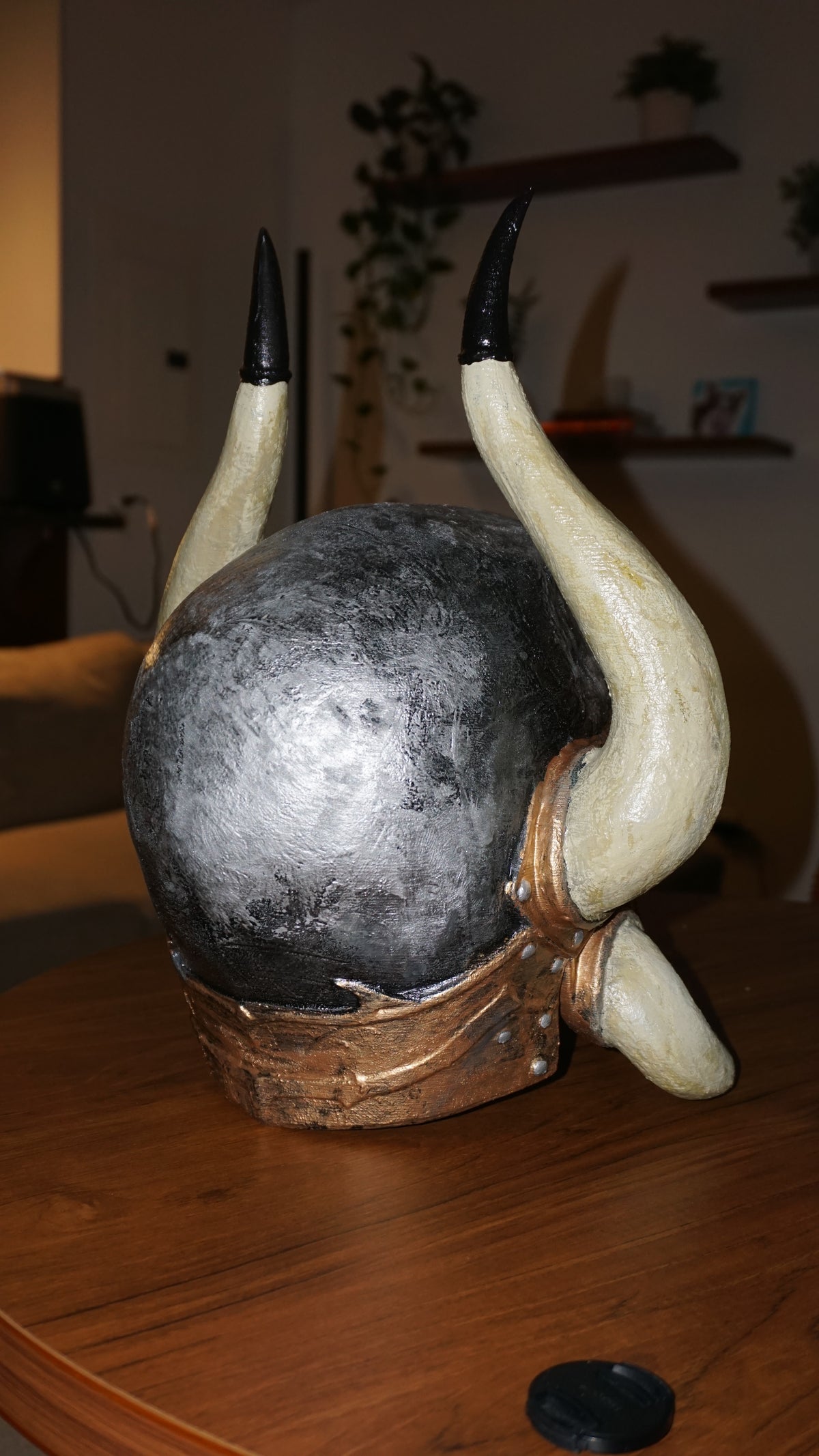 a large, black and white horn-like object with a metallic appearance, placed on a wooden surface.